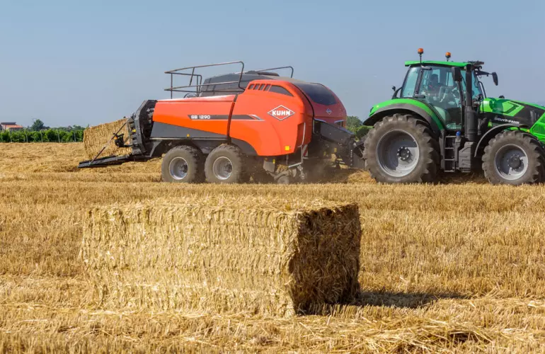 esempio di grande balla quadrata di fieno con una big baler sullo sfondo