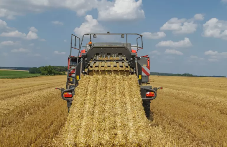vista posteriore di una pressa quadre con una grande balla quadrata appena pressata