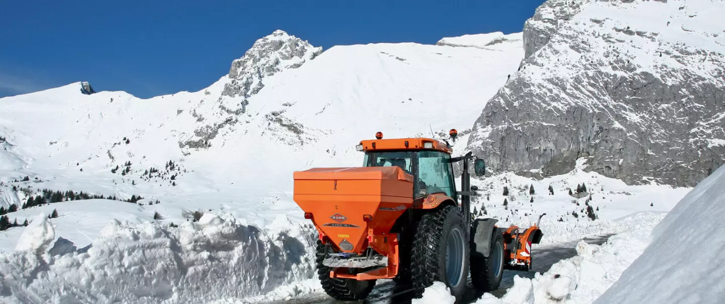 La spandiconcime, spargisale e spargisabbia AXEO al lavoro su una strada di montagna innevata